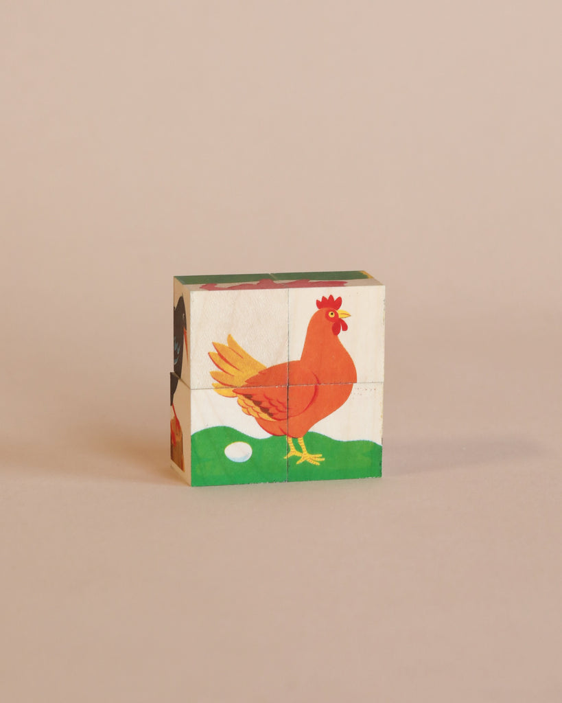 A Wooden Block Puzzle - Mini 4 Piece Domestic Animals painted with the image of a chicken standing on green grass, with an egg beside it, against a solid light pink background.