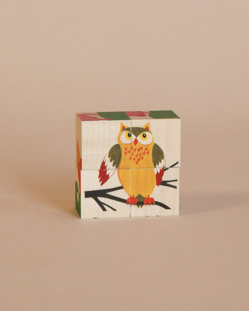 A Wooden Block Puzzle - Mini 4 Piece Domestic Animals assembled to form the image of a colorful owl with wide eyes on a soft beige background.