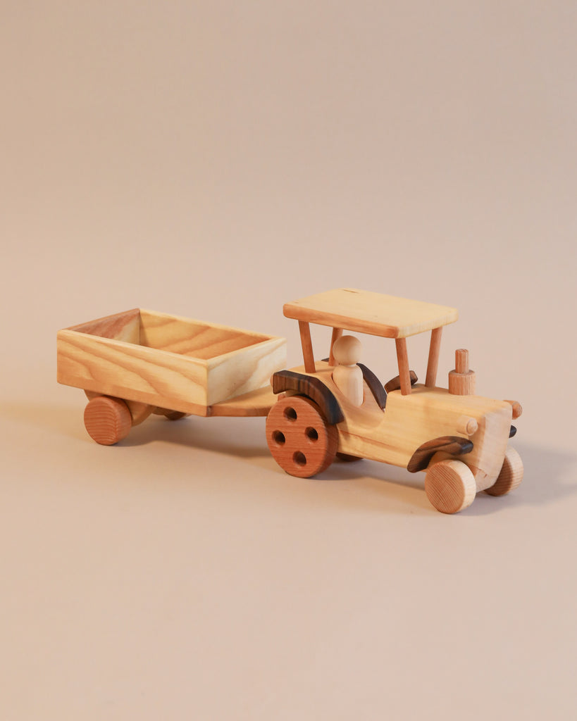 Handmade tractor with a detachable trailer, featuring detailed craftsmanship, set against a neutral background.