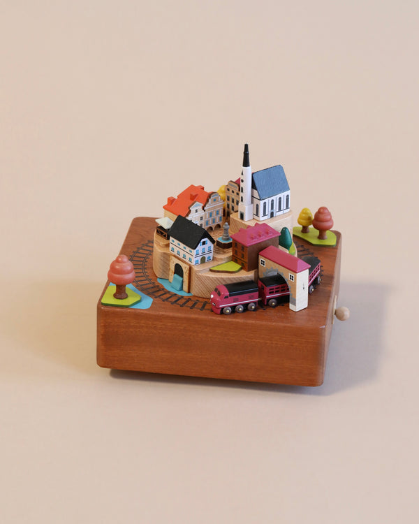 wooden music box with a town in the middle and red train going around it