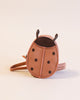 A round, Donsje Mini Leather Backpack - Ladybug with black spots, small antennae, and a crossbody strap, displayed against a plain, light background.
