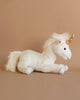 A Steiff unicorn stuffed animal with a white body, gold horn, and fluffy mane and tail, displayed against a soft beige background.