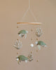 A Handmade Mobile - Ocean Turtles - Final Sale featuring four plush sea turtles and several small felt balls suspended from a wooden ring against a light beige background.
