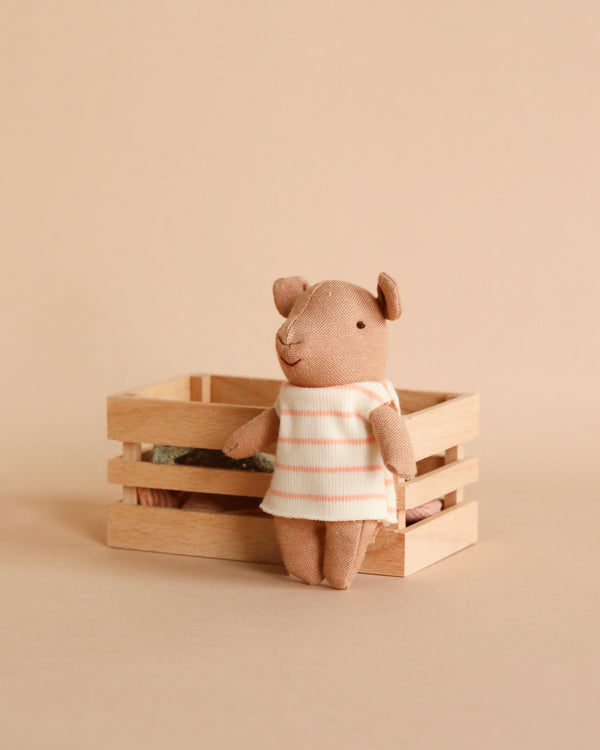 A Maileg Pig In Box, Baby Girl - Pink stands inside a wooden box against a plain beige background.