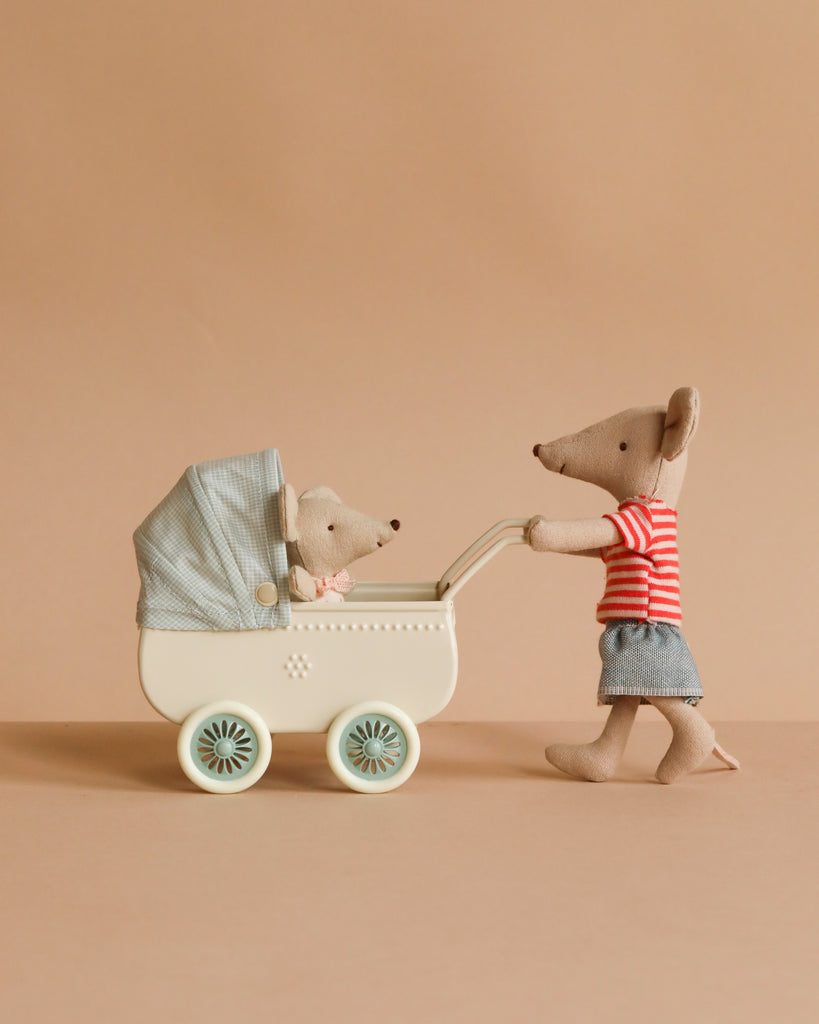The Maileg Sister’s Day Out features a Big Sister Mouse in a red striped shirt and blue skirt, pushing a baby mouse in a vintage pram with blue cover, set against a light brown background and floor.