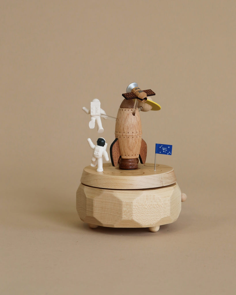 Space themed wooden music box with a rocket in the middle and astronauts and spaceships going around it.
