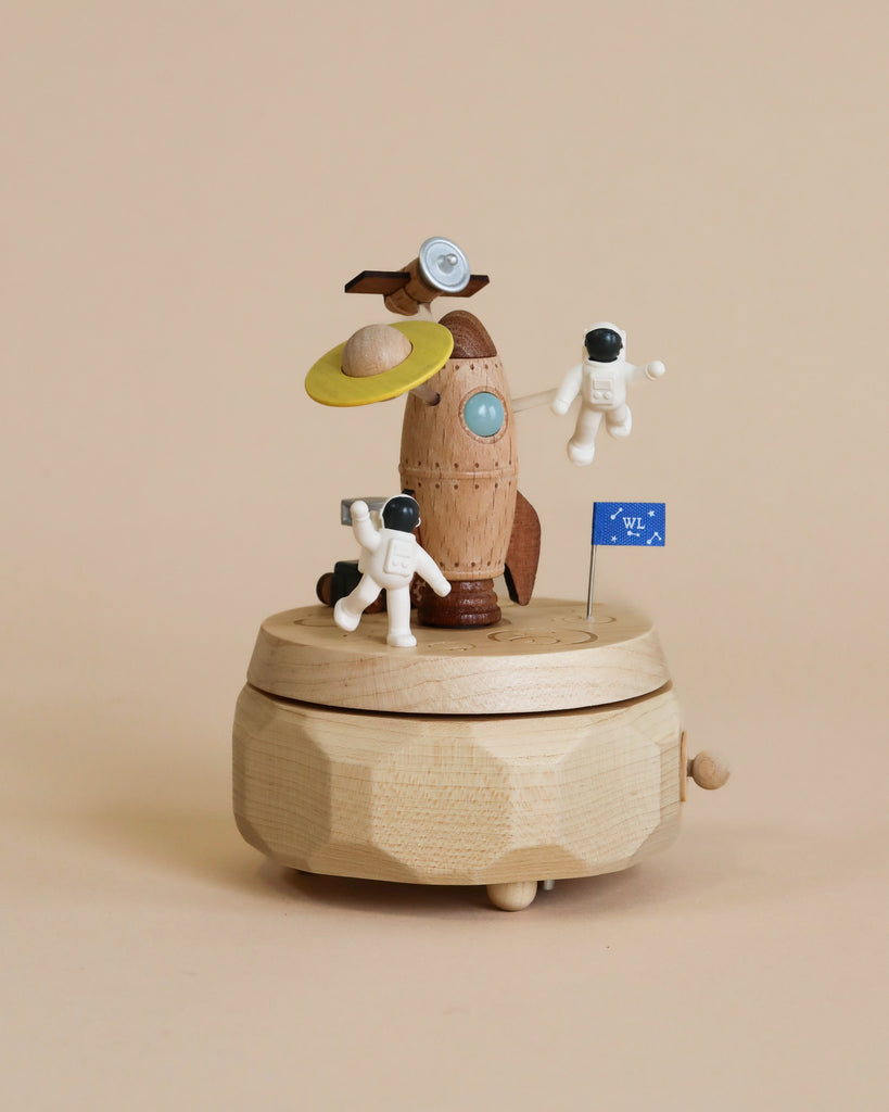 Space themed wooden music box with a rocket in the middle and astronauts and spaceships going around it.
