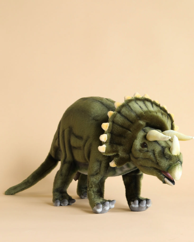 Sentence with replaced product name:
A Triceratops Dinosaur Stuffed Animal, in a standing pose, featuring green fabric with a lighter underbelly and white horns, hand sewn against a plain beige background.