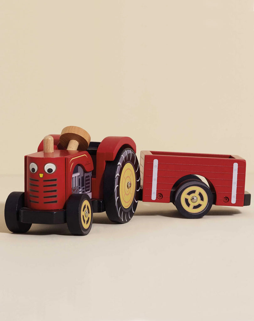 The Farmyard Tractor & Trailer features a red wooden tractor with black and yellow accents, cartoon eyes, and a matching red magnetic trailer with yellow wheels, displayed against a plain background.