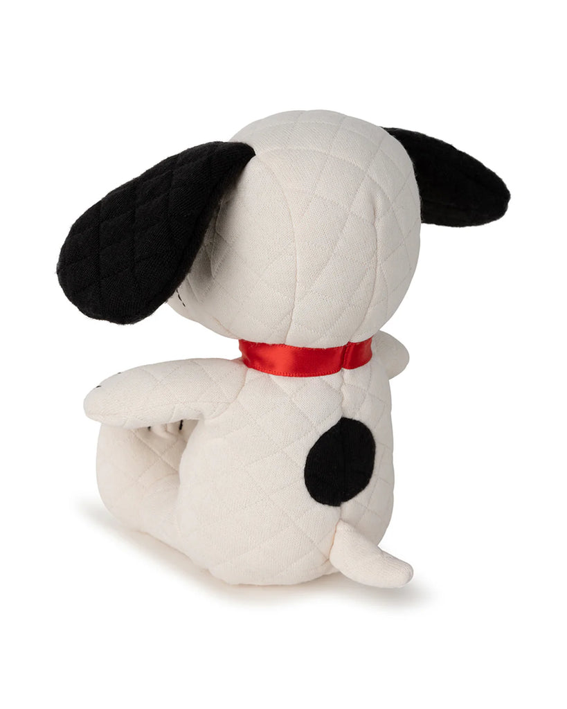The Peanuts Snoopy Plush Toy in Gift Box features a white Snoopy with black ears, a black spot, and quilted texture. Seated upright, it sports a red ribbon and embodies Bon Ton Toys' signature quality—ideal for any Peanuts comic strip enthusiast.