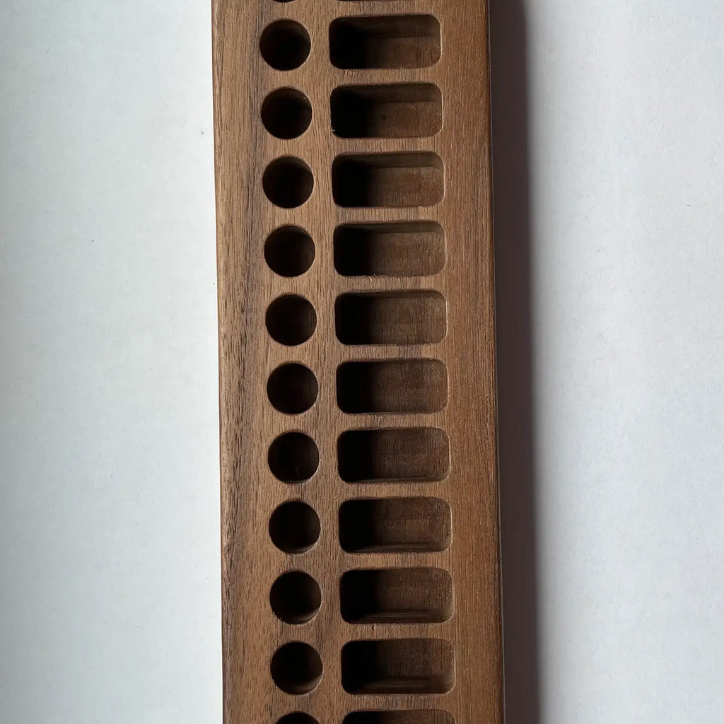A close-up photo of a sustainably sourced Wooden Crayon Holder 12 Stick / 12 Block Slots with multiple circular indentations, each progressively larger, set against a white background.