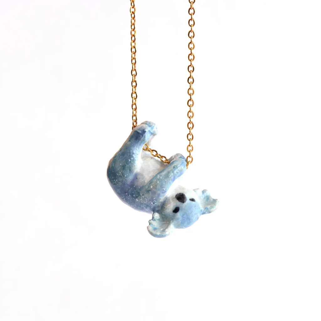 A Galaxy Bear Koala Necklace pendant shaped like a hand-painted blue koala hanging from a 24k gold plated steel chain, set against a plain white background.