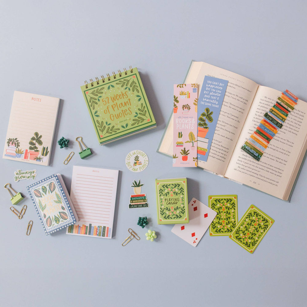 A plant-themed stationery set featuring hand-illustrated notepads, bookmarks, a spiral quote book, paper clips, stickers, and the Green Floral Deck of Playing Cards—ideal for game enthusiasts. Ships in approximately one week.