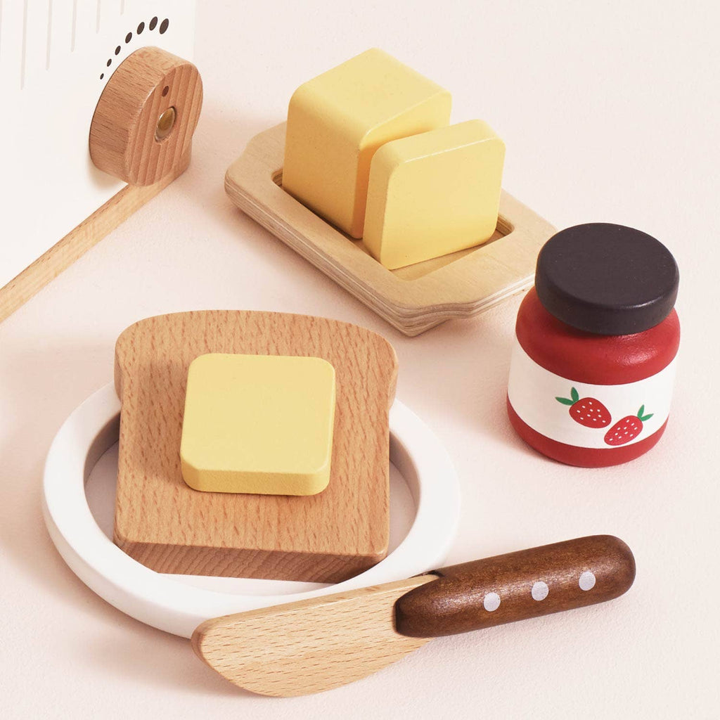 The Pop-up Toaster & Breakfast Set (ships in one week) includes a wooden slice of bread, plate, butter with dish and two pieces, strawberry jar, and knife—all crafted from FSC-certified wood for pretend play.