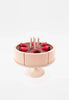 A handmade Chocolate Layer Cake On A Stand toy with removable slices, adorned with strawberry-shaped pieces and candles on a stand, set against a white backdrop.