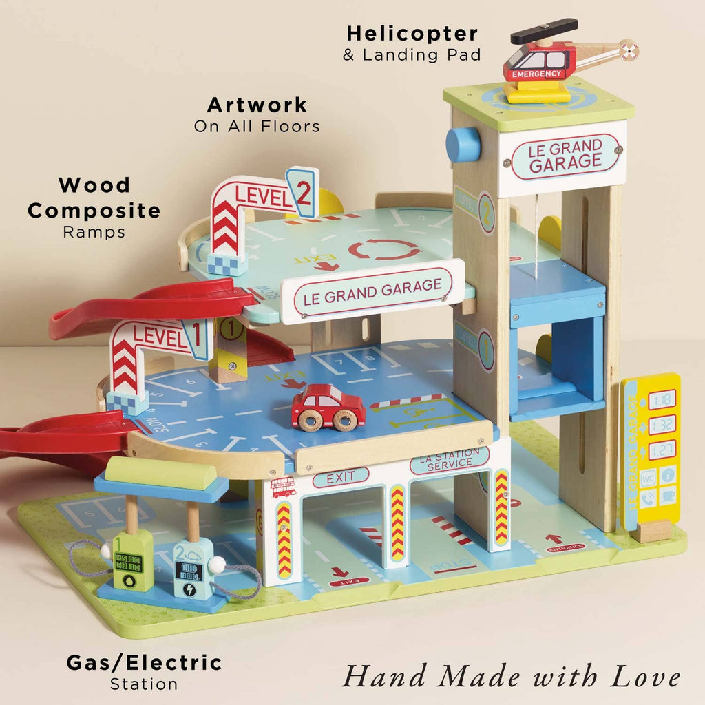 Le Grand Wooden Garage: a handmade playset with ramps, gas/electric station, elevator, floor artwork, red toy car, helicopter with landing pad, and labeled signage—perfect for imaginative play. "Hand Made with Love" at the bottom.