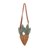 A stylish tan Donsje Chaeso Purse shaped like a heart, adorned with two large grey-green succulent plants, hanging from slender leather straps against a black background.