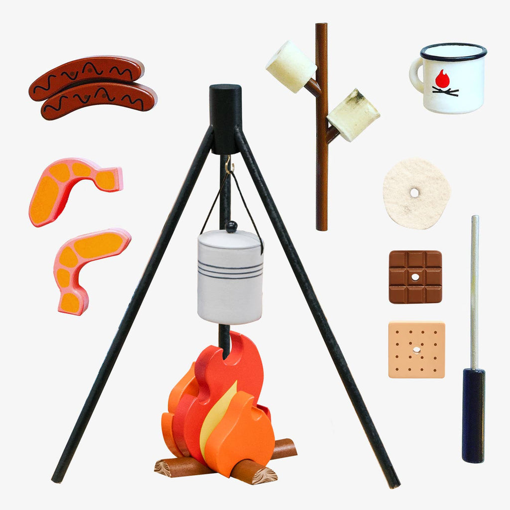 The Wooden Camp Fire Set includes a black tripod, hanging pot, orange/yellow flames, wooden logs, toy food pieces (hotdogs, steak, marshmallows on sticks, chocolate, cracker), mug, and roasting stick for kids' pretend indoor camping fun.