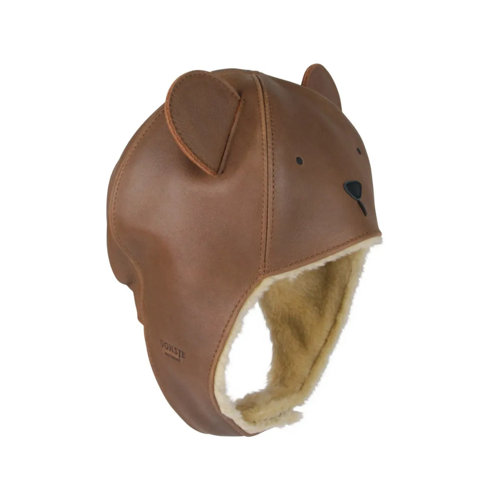 A brown Donsje Leather Classic Hat - Bear with small ears and facial features, lined with faux fur, displayed on a white background.