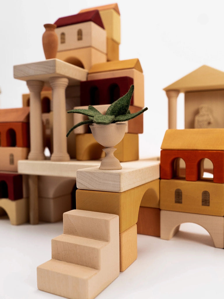 A collection of Sabo Concept Italian Ancient City Blocks arranged to create a miniature Italian seaside town, featuring a small plant set atop a pedestal in the foreground.