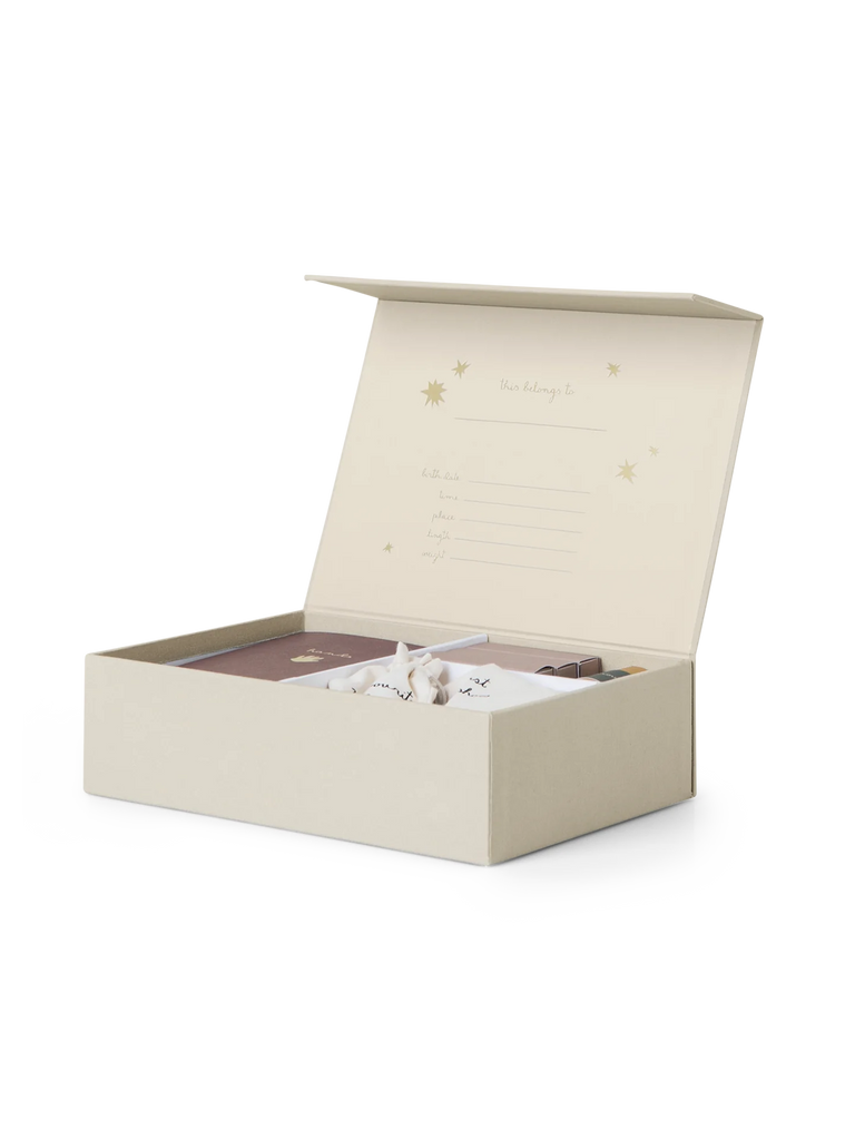 A cream-colored open keepsake box with a hinged lid displays small compartments inside holding various items, including a small toy, a notebook, and a cloth. The inside lid of the Kids Memory Box-The Beginning Of My Life has space for filling in personal information. The box is adorned with star patterns, evoking childhood memories.