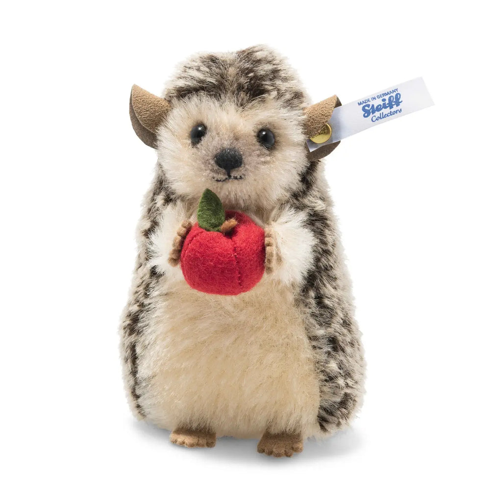 A plush toy Steiff, Ivo Hedgehog with Felt Apple, 4 Inches, featuring small brown ears and a cute expression. It has a blue tag labeled "Steiff Collection" on