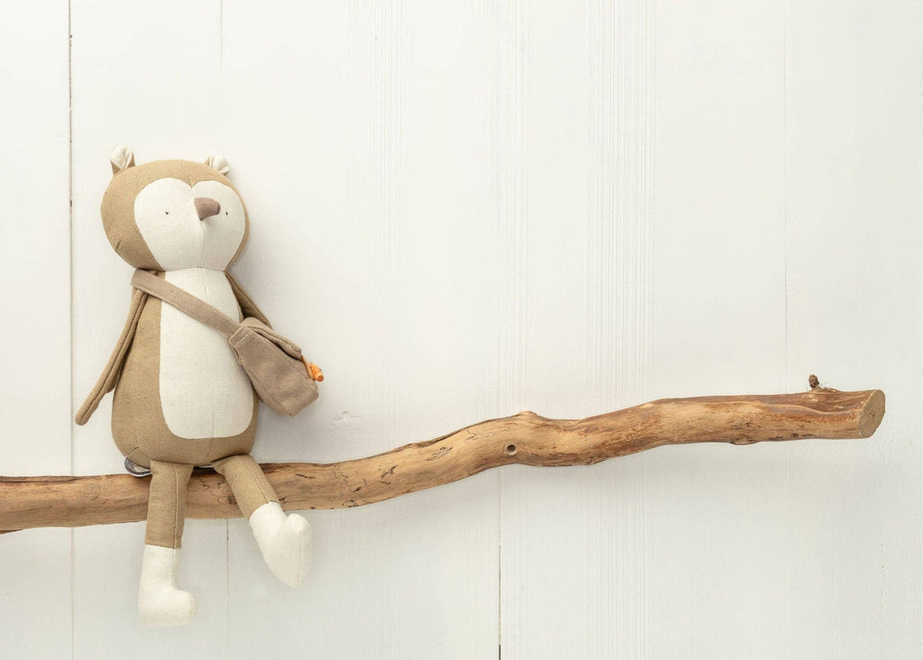 Meet Owen The Owl, a delightful woodland-themed plush toy featuring a beige and white body on a branch. He wears a small brown satchel, ready for enchanting forest adventures.