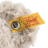 Close-up of a yellow Steiff label on plush fur with text "handmade by Steiff" and the logo, secured with a metal Button in Ear embossed with "Steiff" on it.