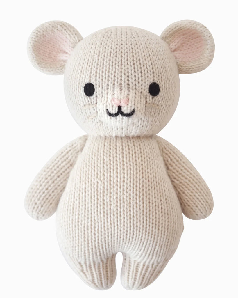 The Cuddle + Kind Baby Mouse is a cream-colored, hand-knit stuffed animal made from natural Peruvian cotton yarn, featuring round ears, black eyes, a pink nose, and a cute smile—all set against a plain white background.