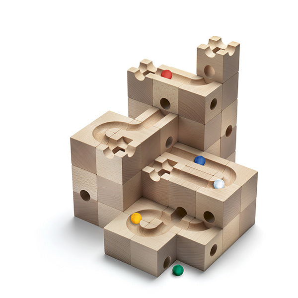 A Cuboro 50 Marble Run Starter Set with interlocking blocks and channels, featuring several marbles in red, yellow, blue, and green positioned on and within the structure, set against a plain