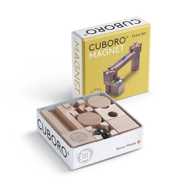 A Cuboro Magnet Marble Run Extra Set shown with its box, featuring wooden blocks and marbles for constructing a marble run system, labeled "Swiss made.