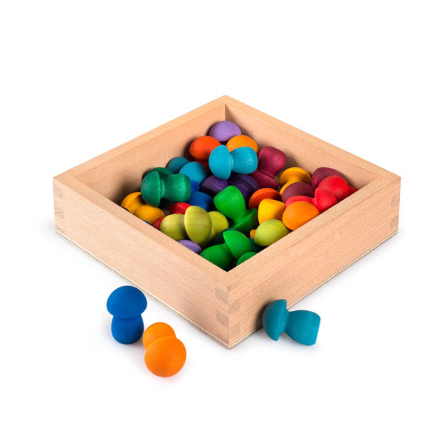 The Grapat Small Storage Box, crafted from sustainably sourced wood, is filled with colorful mushroom-shaped pieces in blue, yellow, orange, red, purple, and green. Some vibrant pieces spill playfully outside the box onto the surface.