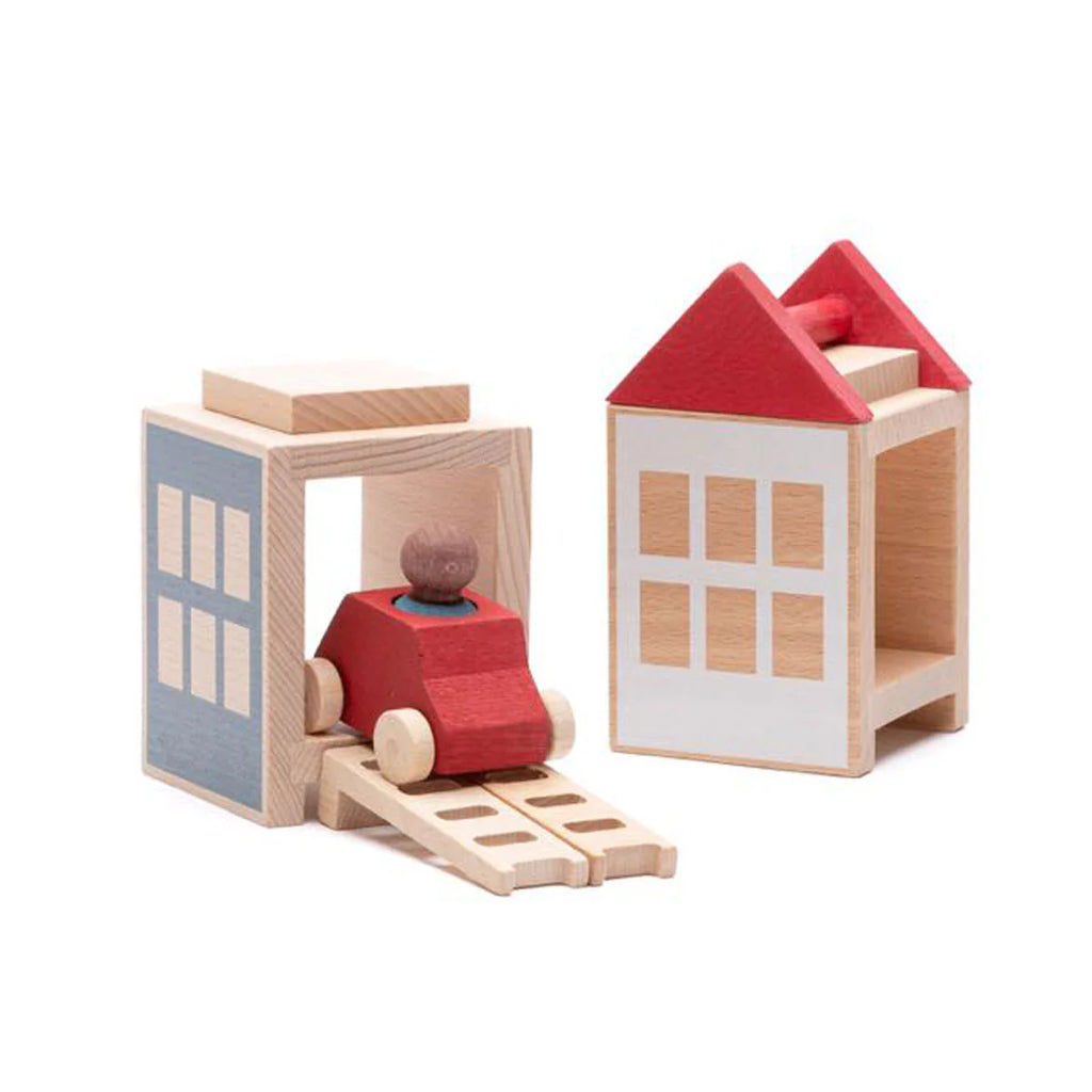 The Lubulona Lubu Town Summerville Set features two wooden buildings—one blue, one white with a red roof—and a wooden toy car with a red body and figure on a ramp exiting one building.