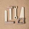 Sentence with Product Name: Heirloom quality Wooden Tool Set including a hammer, screwdriver, wrench, and saw arranged on a sandy background.