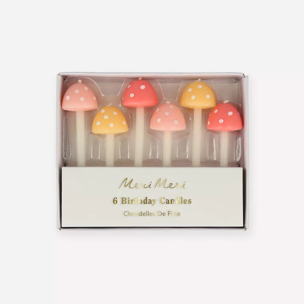 A box of six Meri Meri Mushroom Birthday Candles shaped like colorful mushrooms with red, orange, and white caps, perfect for a fairy garden party.