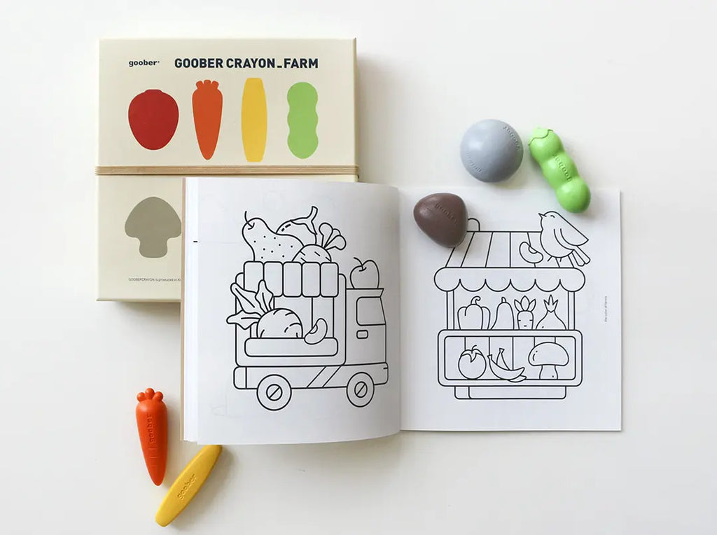 A children's coloring book open to a page with drawings of fruits and vegetables in a truck, accompanied by Farm Crayons that include a carrot and a mushroom.