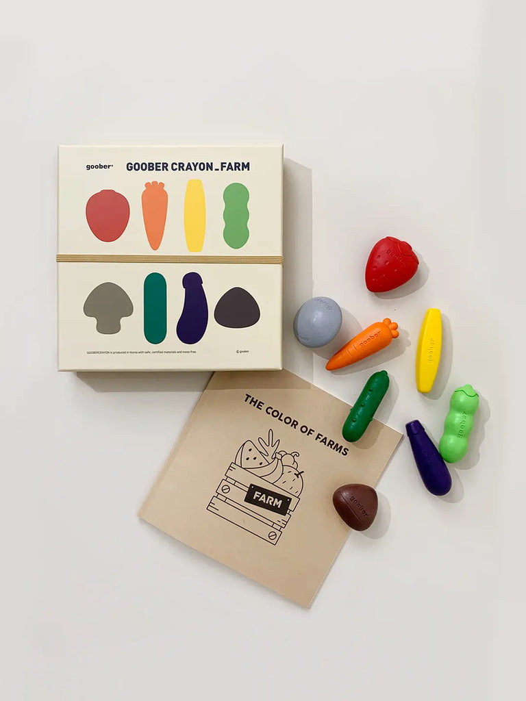 A photo of Farm Crayons box with several uniquely shaped farm crayons resembling farm produce, displayed beside a coloring book titled "The Color of Farms.
