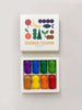 A box of non-toxic Peanut Crayons with colorful, bean-shaped crayons neatly arranged in a white tray, each in a different vibrant color, displayed next to its closed box lid featuring a