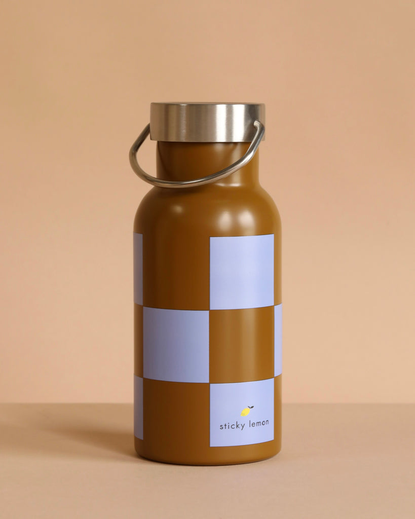 A stainless steel Sticky Lemon Water Bottle | Farmhouse in soil green and blooming purple with a silver cap and handle, the small "sticky lemon" logo on the lower front, set against a beige background.