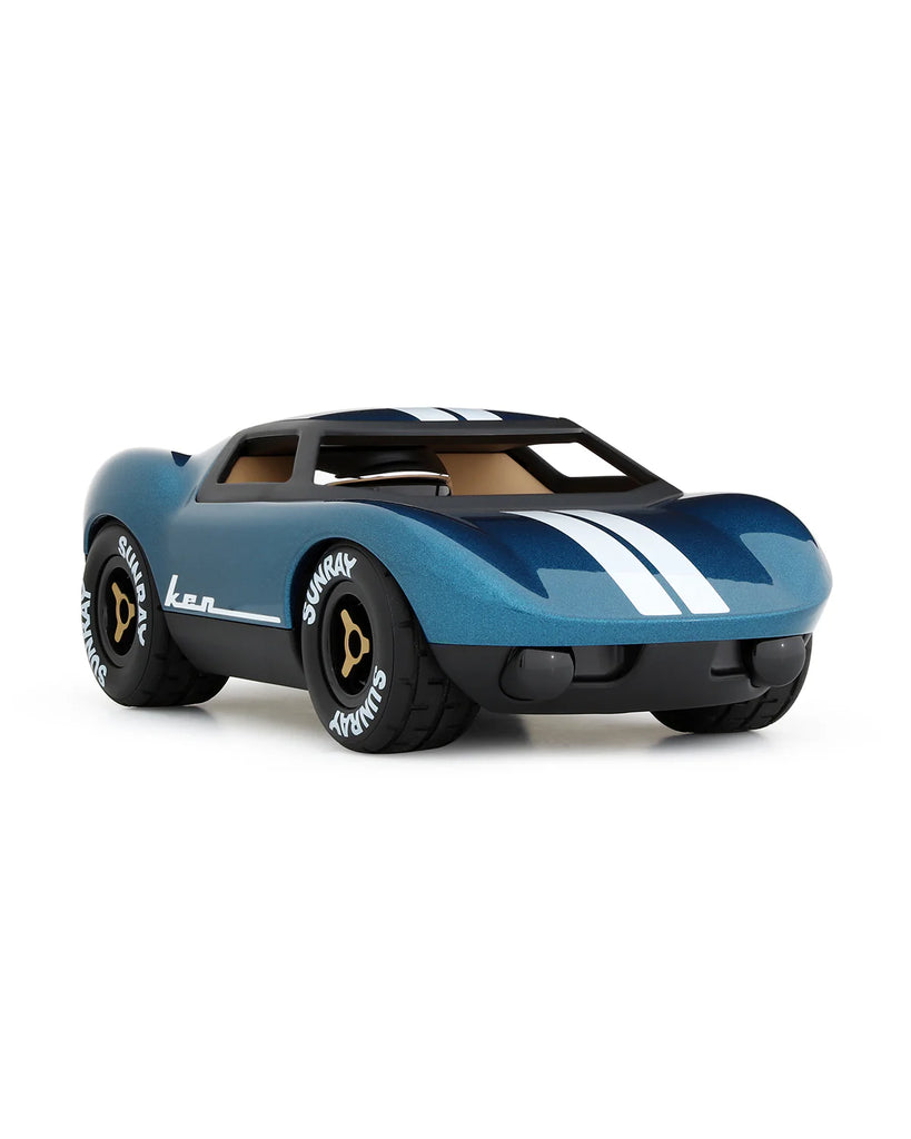 The Playforever MINI KEN CASH Blue features white stripes, black tires with "SUNDAY" written on them, gold rims, and a low, sleek design. This classic toy racing car is shown on a white background.