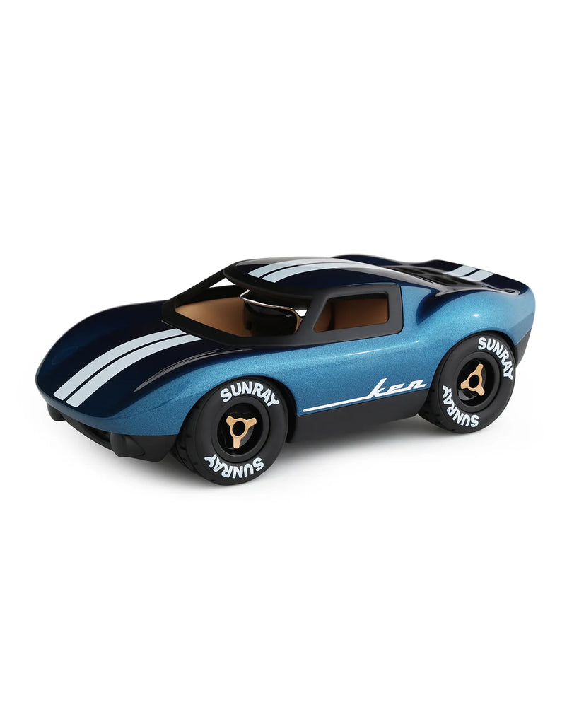 The Playforever MINI KEN CASH Blue is a classic blue toy car featuring white racing stripes, black-tinted windows, "SUNRAY" tires, gold and black rims, and "Ken" on the side—evoking the spirit of a Ken Miles car.