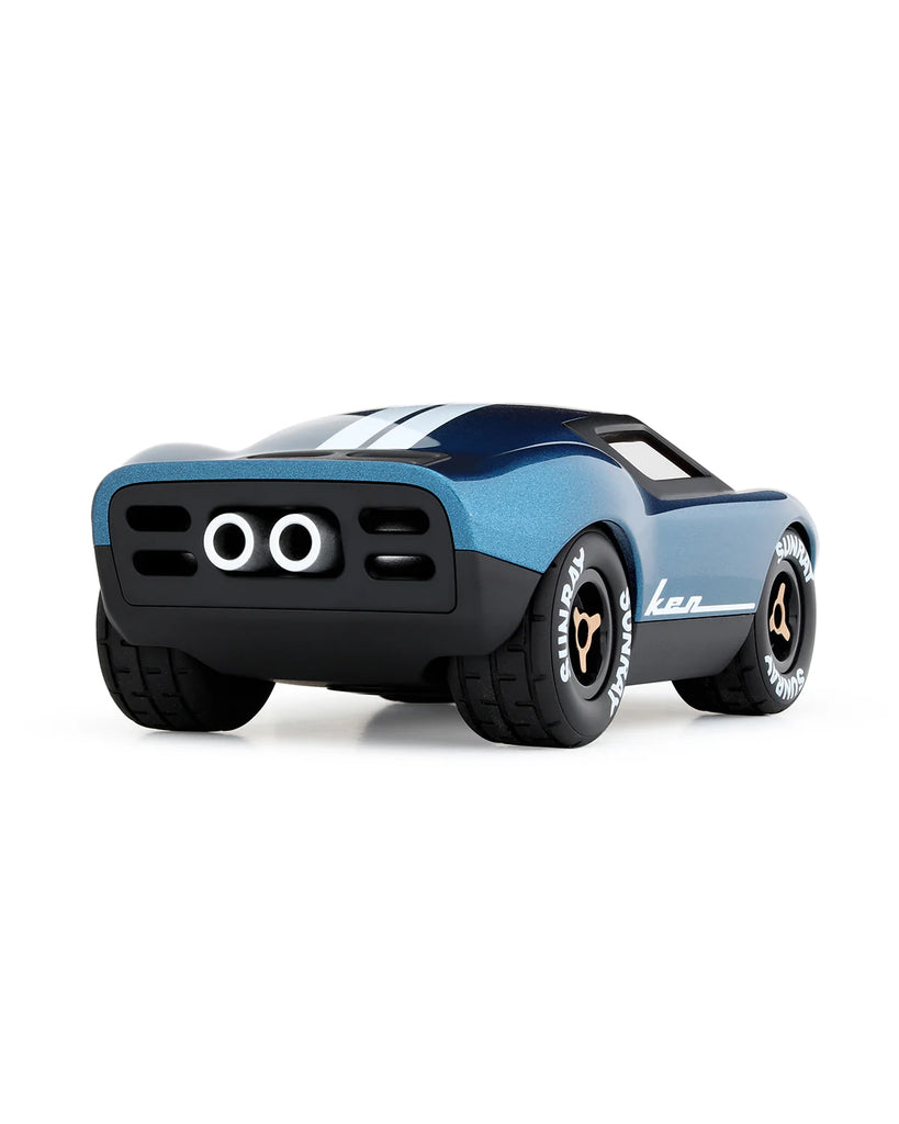 The Playforever MINI KEN CASH Blue racing car, seen from the rear left, features white stripes, wide tires with "Kan" branding, and two rear exhaust pipes—a classic toy car design.