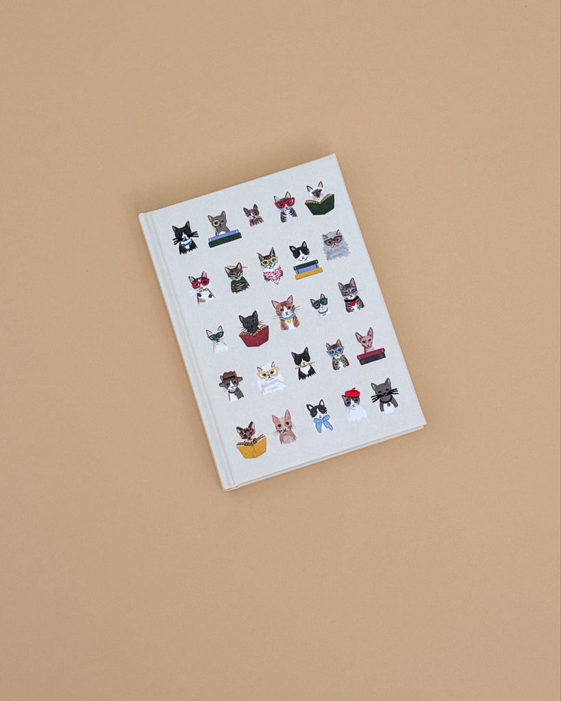 The Studious Cats Embroidered Journal features a white cover adorned with embroidered cats in playful poses and accessories, making it an ideal gift for any cat lover.