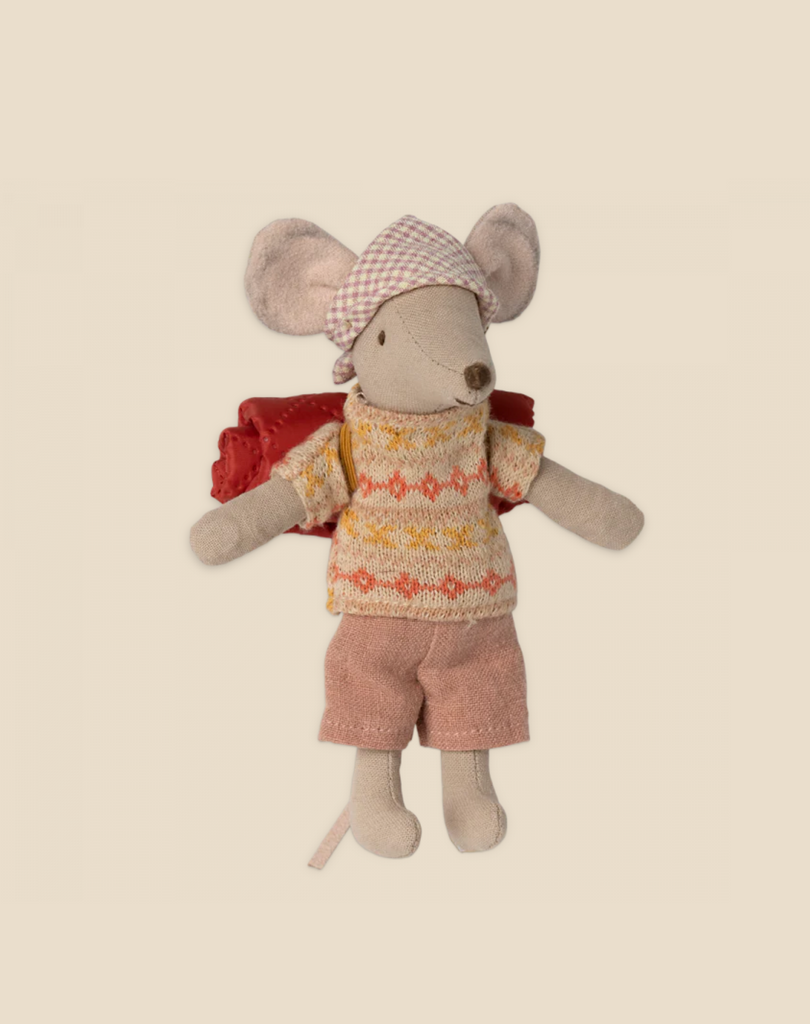 A small Maileg Hiker Mouse, Big Sister dressed in a knitted sweater with a geometric pattern, pink shorts, and a checkered headscarf. The mouse has a red backpack on its back, perfect for a hiking trip, and is standing upright on a neutral background. Part of the hiker collection, it embodies the spirit of wild nature exploration.