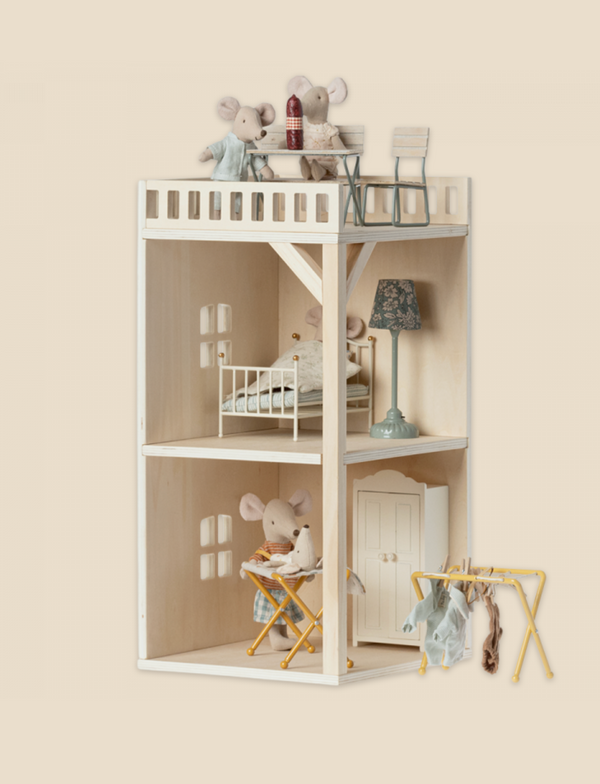 A charming wooden dollhouse featuring two levels; the top with a balcony and a bed, housing toy mice, and the lower level designed as a Maileg Farmhouse - Annex Bonus Room. Soft pastel tones and miniature furniture add to the cozy feel.