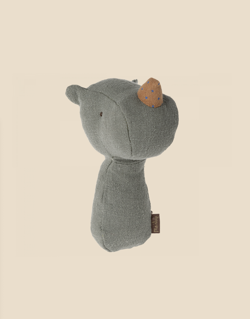 A small, stuffed animal toy resembling a bear stands against a beige background. The toy is made of grey fabric with a brown snout featuring blue polka dots and small, sewn-on eyes. A brown tag is attached to its side. This adorable piece makes a perfect gift for babies and comes tucked in a charming gift box.
Product Name: Maileg Lullaby Friend Rattles, Rhino - Pine