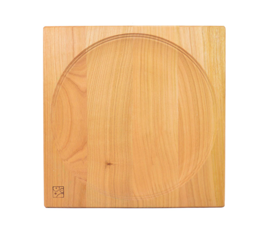 The Cherry Wood Spinning Plate features a square design with a central circular indentation and a small corner logo, displayed on a white background.