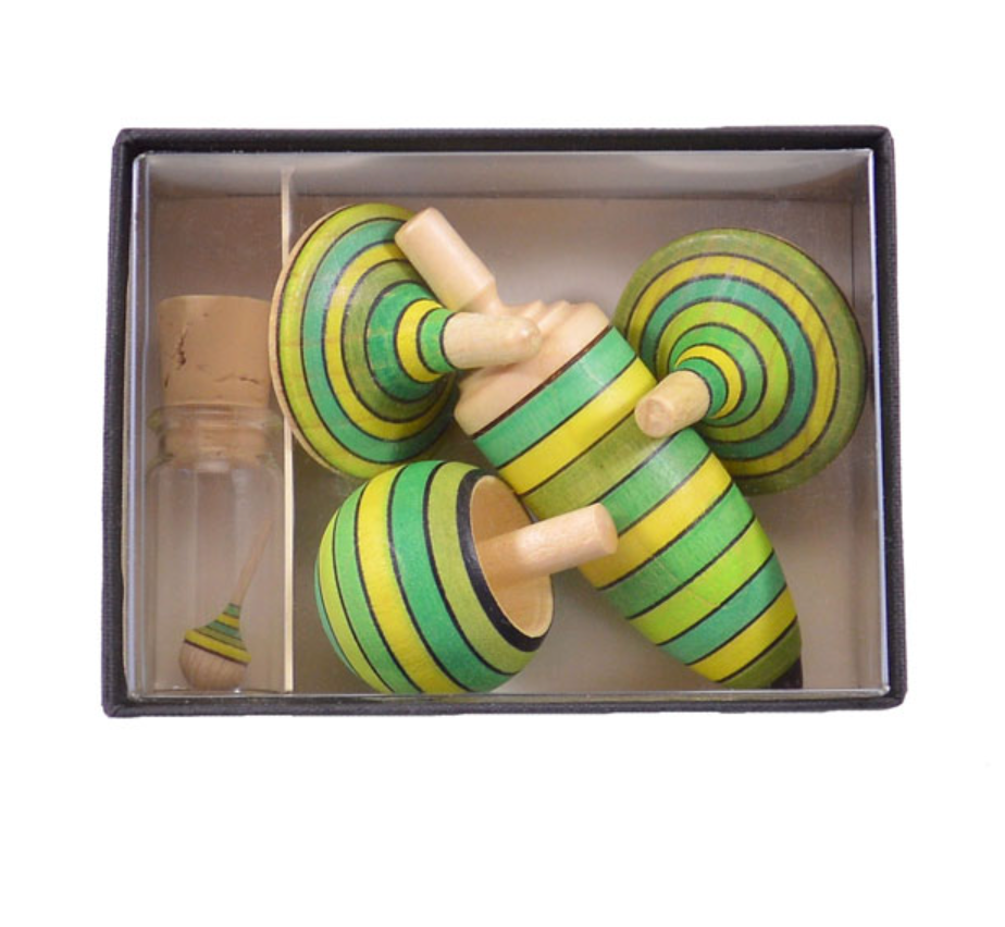 The Spinning Top Champion Learning Set - Grass includes four striped tops in green, yellow, and black plus a glass vial with a mini top. Suitable for all skill levels and crafted to meet toy safety standards.