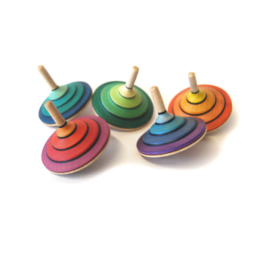 A Mader Tango Spinning Top in vivid orange, crafted from maple wood and adorned with colorful concentric circles, is showcased against a white background.