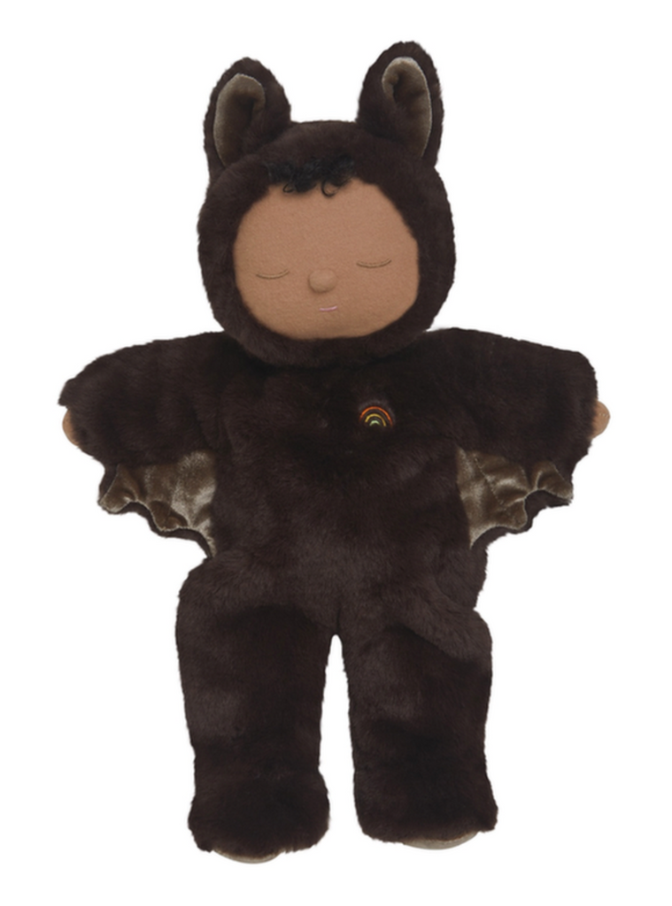 The Olli Ella Cozy Dinkum - Bat Ozzie - Dark Umber is a plush bedtime doll in a brown bat costume with ears, wings, closed eyes, a gentle smile, and a rainbow chest patch—perfect for cuddles and sweet dreams.